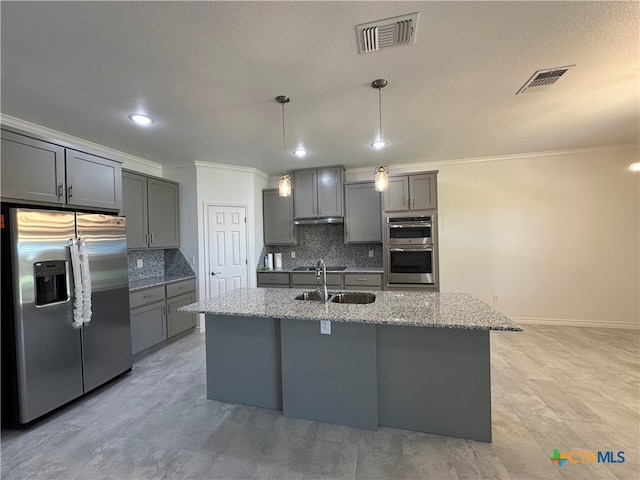 kitchen with decorative backsplash, stainless steel appliances, gray cabinetry, and light stone countertops