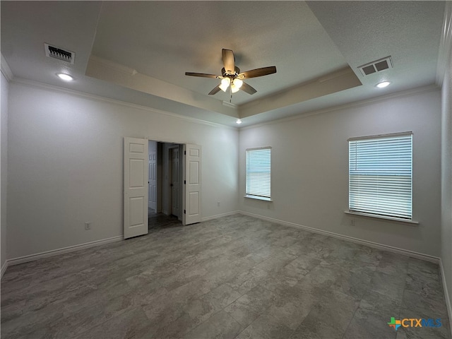 empty room with crown molding, ceiling fan, and a raised ceiling