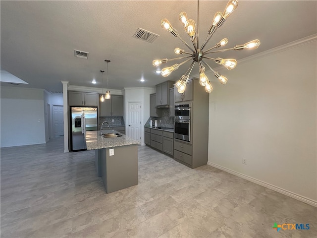 kitchen with appliances with stainless steel finishes, gray cabinets, decorative backsplash, sink, and an island with sink