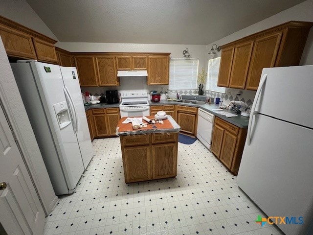 kitchen with a center island, white appliances, vaulted ceiling, and sink