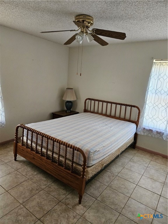 tiled bedroom with a textured ceiling and ceiling fan