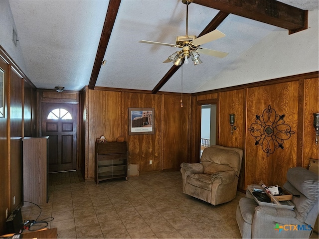 living room with vaulted ceiling with beams, wood walls, ceiling fan, and a textured ceiling