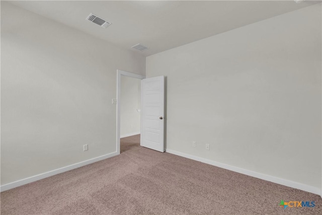 carpeted spare room featuring baseboards and visible vents