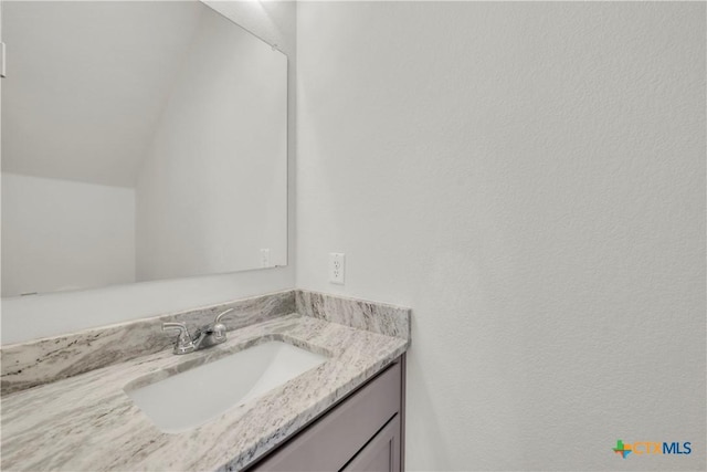 bathroom featuring lofted ceiling and vanity