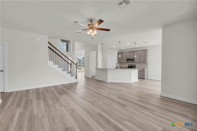 unfurnished living room featuring light wood-style flooring, visible vents, and ceiling fan