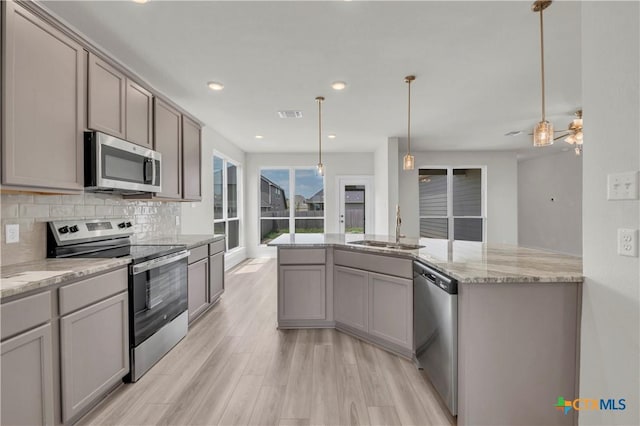 kitchen with a sink, backsplash, appliances with stainless steel finishes, gray cabinetry, and visible vents