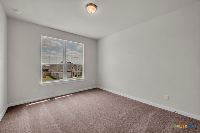 carpeted empty room featuring baseboards