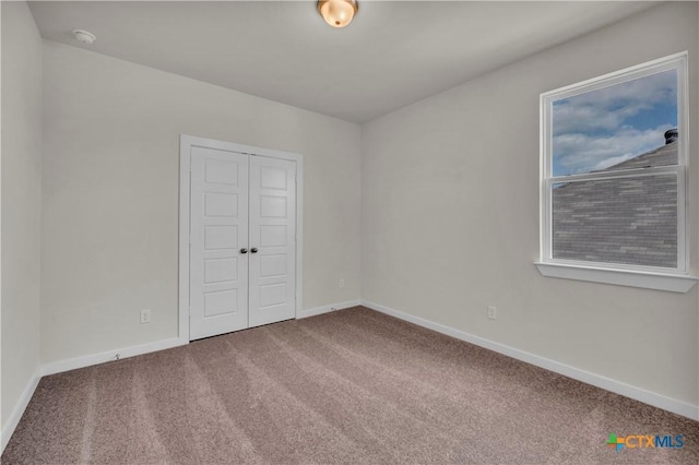 unfurnished room with baseboards and carpet