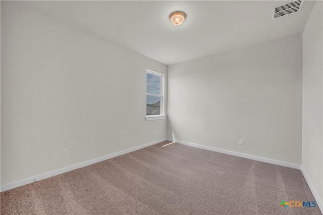 spare room featuring baseboards, visible vents, and carpet