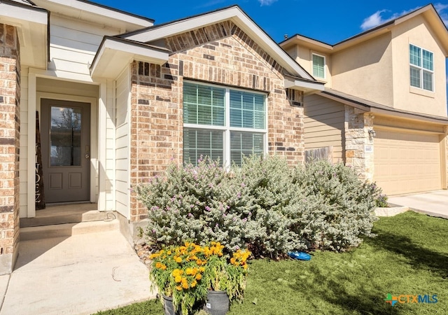 doorway to property with a garage and a yard