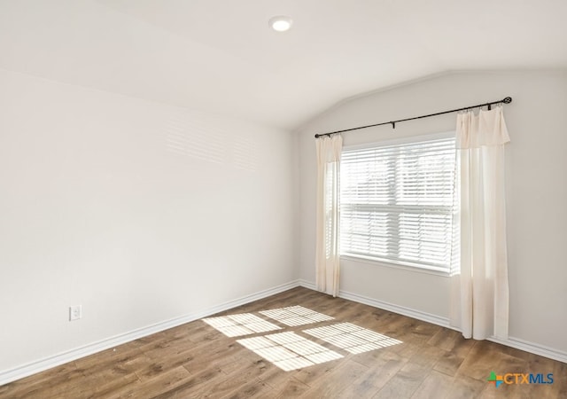 unfurnished room with vaulted ceiling and hardwood / wood-style flooring