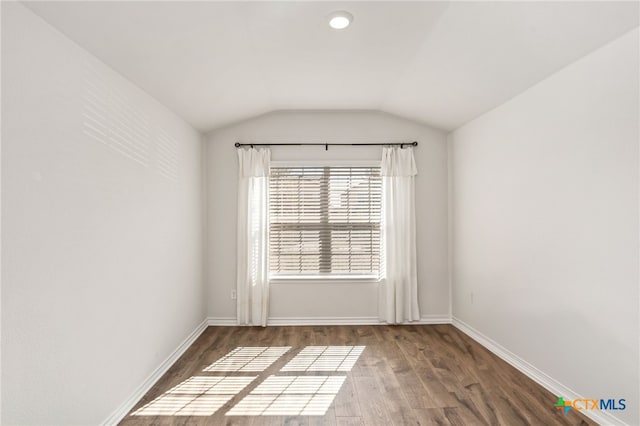 spare room with hardwood / wood-style floors and lofted ceiling