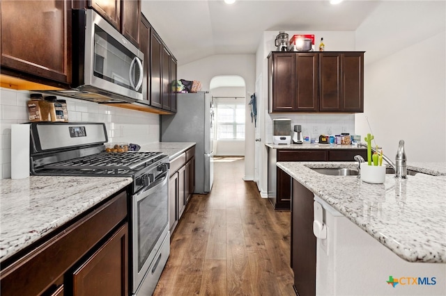 kitchen featuring tasteful backsplash, appliances with stainless steel finishes, wood-type flooring, and vaulted ceiling