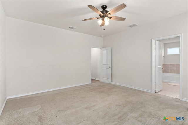 unfurnished bedroom with connected bathroom, light colored carpet, and ceiling fan