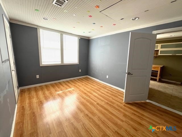 unfurnished bedroom featuring ornamental molding and light hardwood / wood-style floors