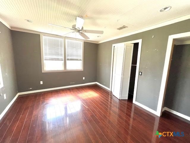 unfurnished bedroom featuring crown molding, dark hardwood / wood-style flooring, and a closet