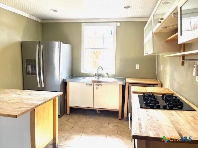 kitchen with ornamental molding, butcher block counters, sink, and stainless steel fridge