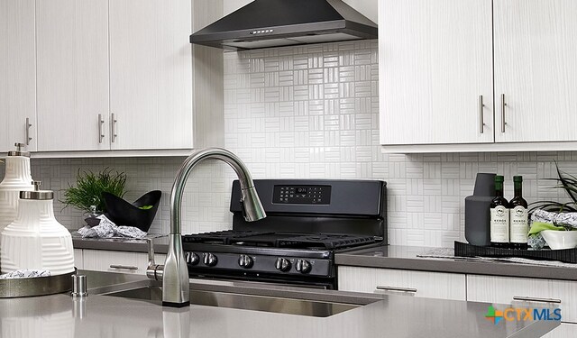 kitchen with tasteful backsplash, wall chimney range hood, and sink