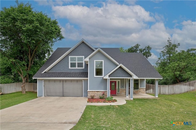 craftsman-style home with fence, covered porch, a front yard, and concrete driveway