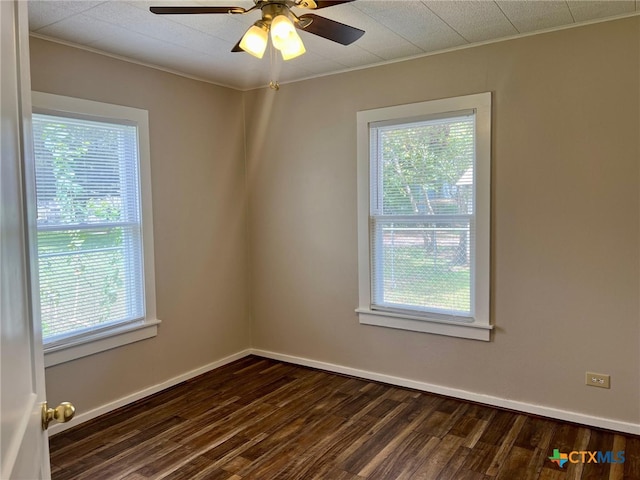 unfurnished room featuring dark wood-type flooring, a wealth of natural light, ceiling fan, and ornamental molding