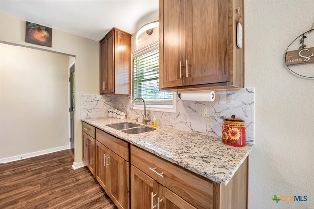 kitchen with tasteful backsplash, light stone countertops, sink, and dark hardwood / wood-style floors