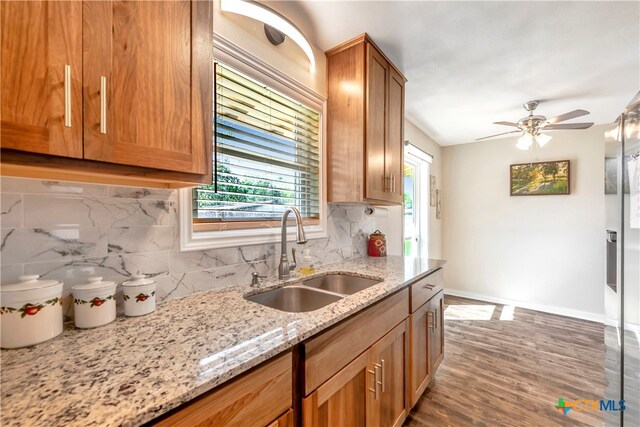 kitchen with light stone countertops, backsplash, ceiling fan, sink, and dark hardwood / wood-style floors