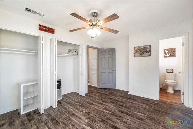 unfurnished bedroom featuring multiple closets, ceiling fan, ensuite bath, and dark wood-type flooring