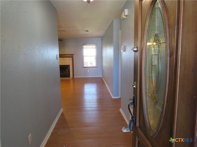 hall with visible vents, wood finished floors, and baseboards