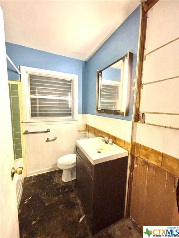 bathroom with walk in shower, vanity, toilet, and tile walls