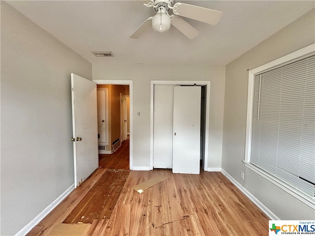 unfurnished bedroom with light wood-type flooring, ceiling fan, and a closet