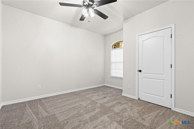 carpeted spare room featuring ceiling fan