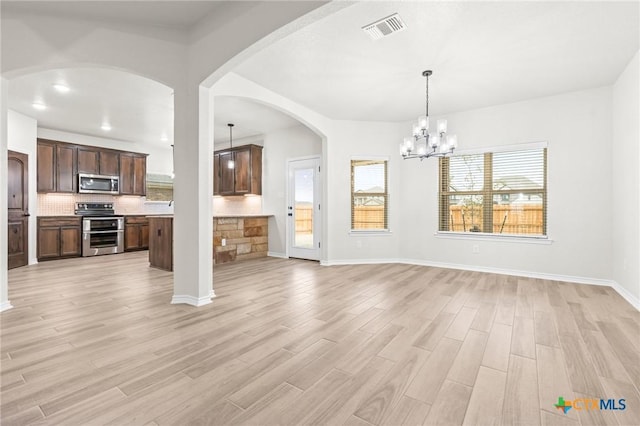 unfurnished living room featuring a notable chandelier and light hardwood / wood-style floors