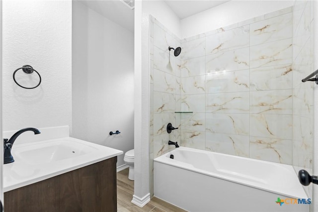 full bathroom featuring tiled shower / bath, wood-type flooring, vanity, and toilet