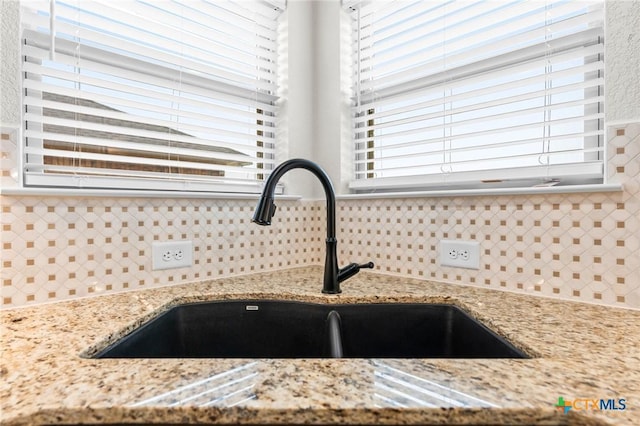 room details with tasteful backsplash, sink, and light stone counters