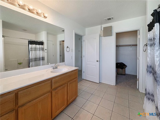 408 Rowdy Dr, Killeen, TX 76542 - full bath with vanity, tile patterned flooring, a spacious closet, a textured ceiling, and a shower with shower curtain