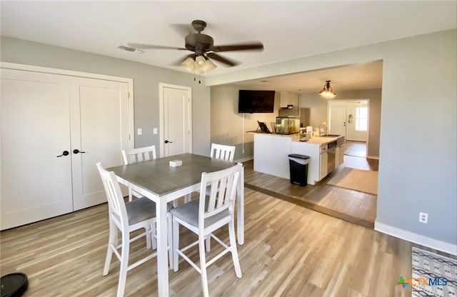 dining area featuring sink, light wood-type flooring, and ceiling fan