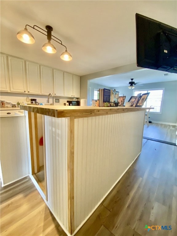 kitchen featuring sink, white cabinetry, kitchen peninsula, and hardwood / wood-style floors