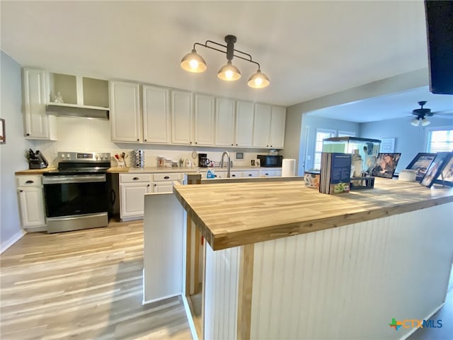 kitchen with pendant lighting, white cabinets, wooden counters, electric range, and light hardwood / wood-style flooring