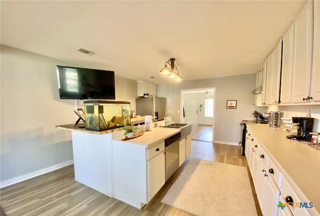 kitchen with light hardwood / wood-style floors, white cabinets, decorative light fixtures, sink, and stainless steel appliances