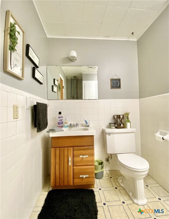 bathroom featuring tile walls, toilet, vanity, and ornamental molding