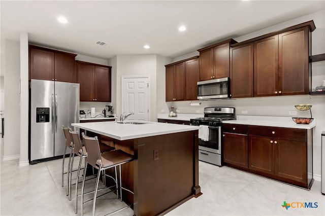 135 Mary Max Cir, San Marcos, TX 78666 - kitchen with appliances with stainless steel finishes, a sink, light countertops, a kitchen bar, and an island with sink