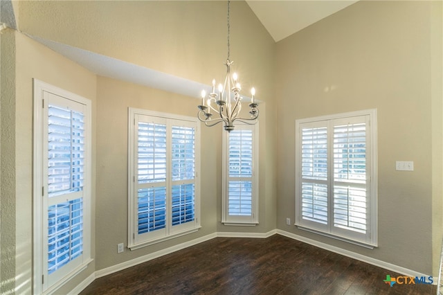 unfurnished dining area featuring vaulted ceiling, a healthy amount of sunlight, dark hardwood / wood-style flooring, and a notable chandelier