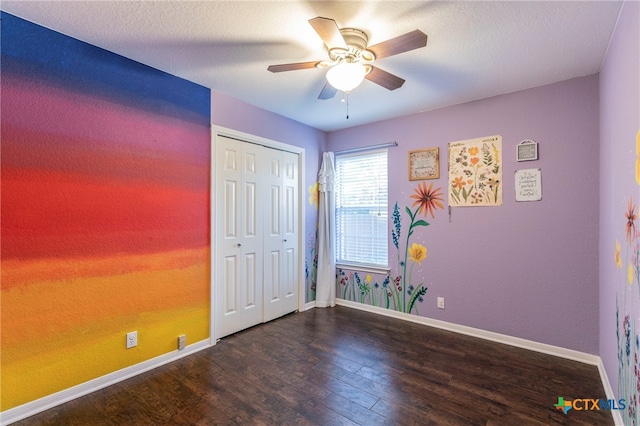 unfurnished bedroom with dark wood-type flooring, ceiling fan, a textured ceiling, and a closet