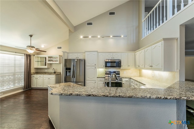 kitchen featuring kitchen peninsula, appliances with stainless steel finishes, dark hardwood / wood-style floors, high vaulted ceiling, and white cabinets