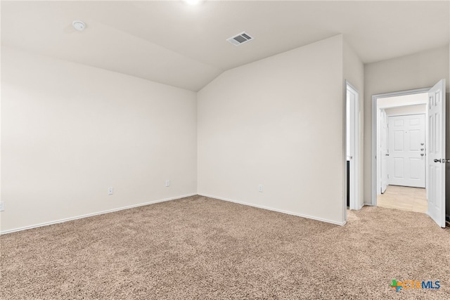 carpeted spare room with vaulted ceiling