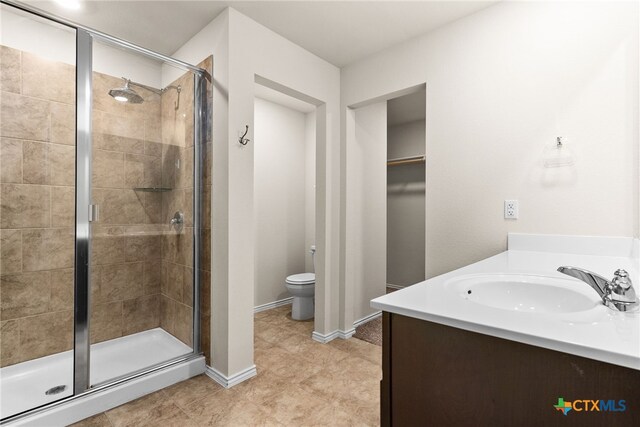 bathroom with tile patterned flooring, toilet, vanity, and walk in shower