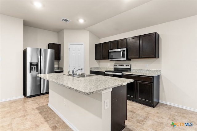 kitchen featuring dark brown cabinetry, stainless steel appliances, vaulted ceiling, sink, and an island with sink