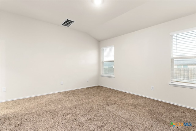 carpeted spare room with vaulted ceiling