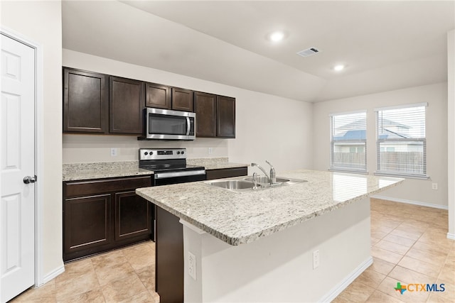 kitchen with sink, an island with sink, dark brown cabinets, light tile patterned flooring, and stainless steel appliances