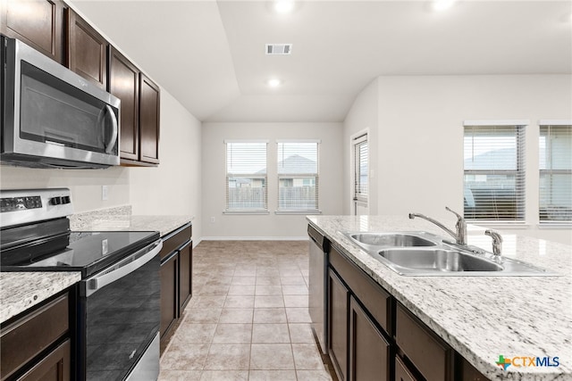 kitchen featuring a healthy amount of sunlight, light tile patterned floors, stainless steel appliances, and lofted ceiling